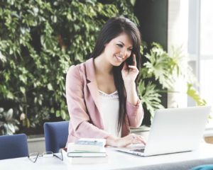 Picture of a women on the phone while working on a notebook computer