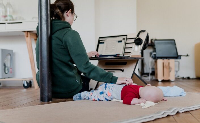 Picture of a young mother working from home with a sleeping baby next to her