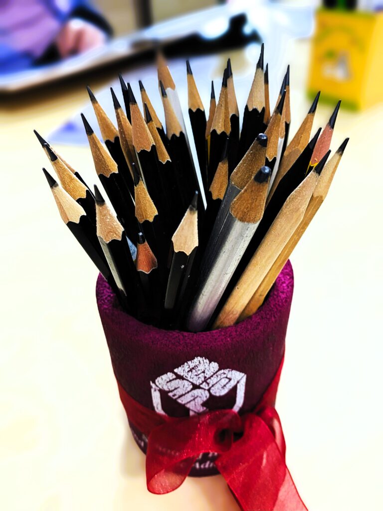 A bunch of pencils inside a pencil holder, all facing up.